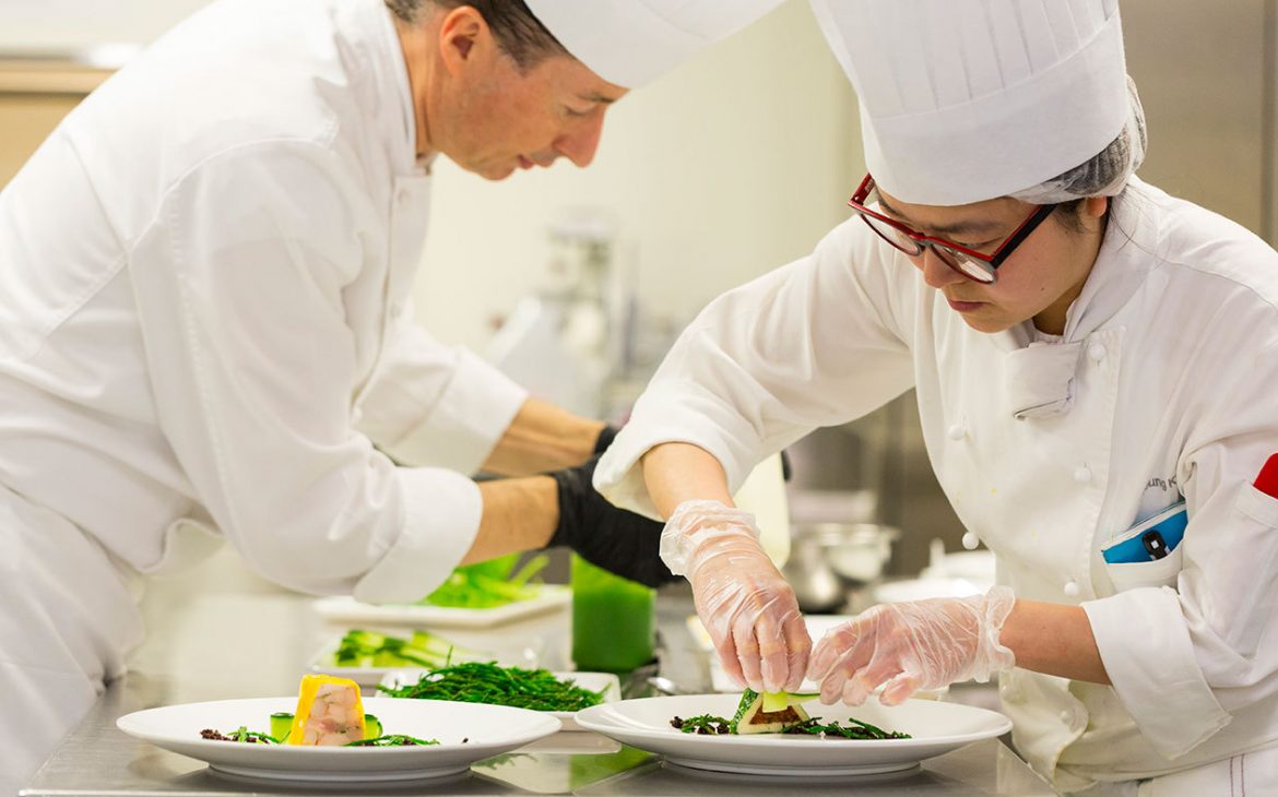 A man and woman preparing food in a kitchen